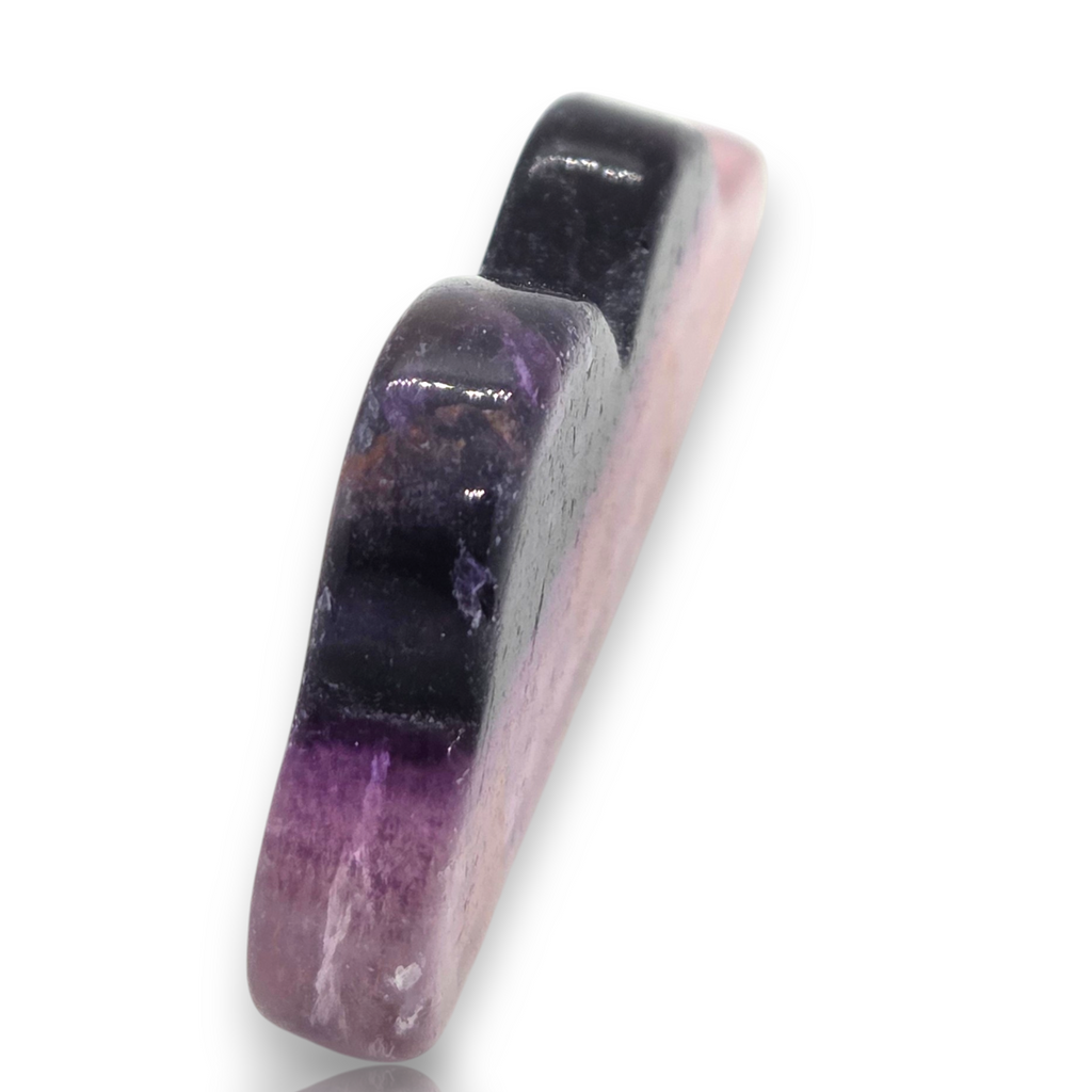 A polished gemstone cabochon with a distinct color transition from deep purple to pink, displayed on a clean white background