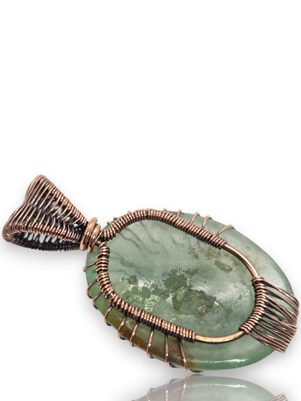 A handmade oval pendant featuring a green stone wrapped in copper-colored wire, shown on a white background 