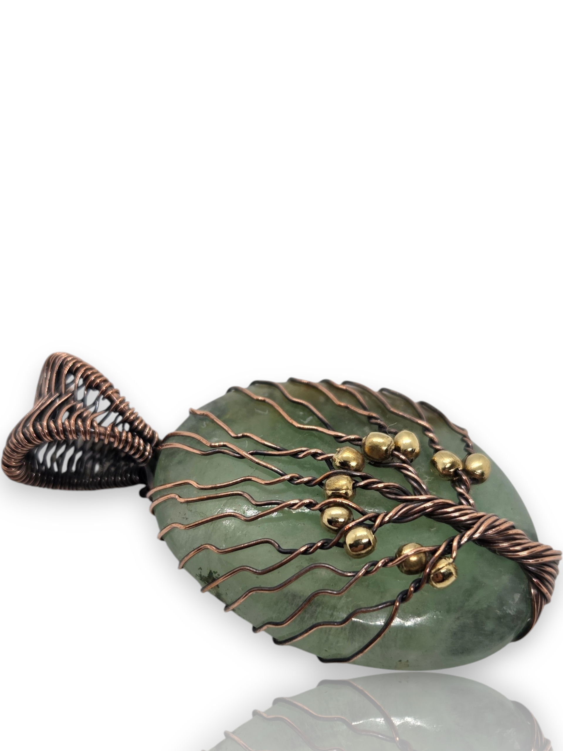 A fish-shaped pendant with a green stone body and copper wire wrapping, featuring small gold beads, shown on a white background 