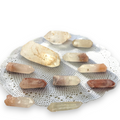 Crystal Chrysalis Haus A collection of natural quartz crystal points in various earthy tones of beige, brown, and translucent white, arranged on a white lace doily 