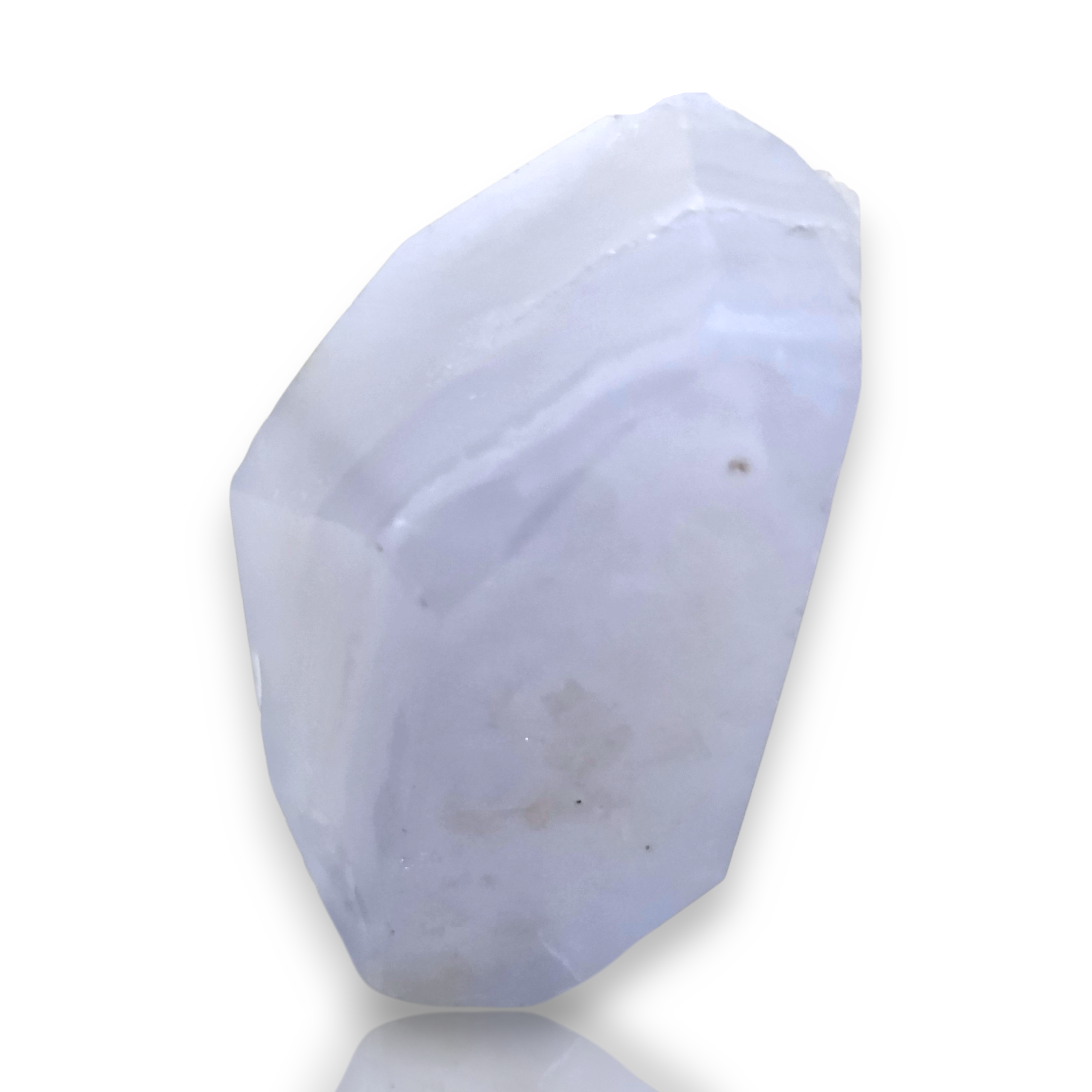 Crystal Chrysalis Haus A faceted raw crystal stone with a pale lavender-blue hue and natural rough edges, displayed on a clean white background with a soft reflection. 