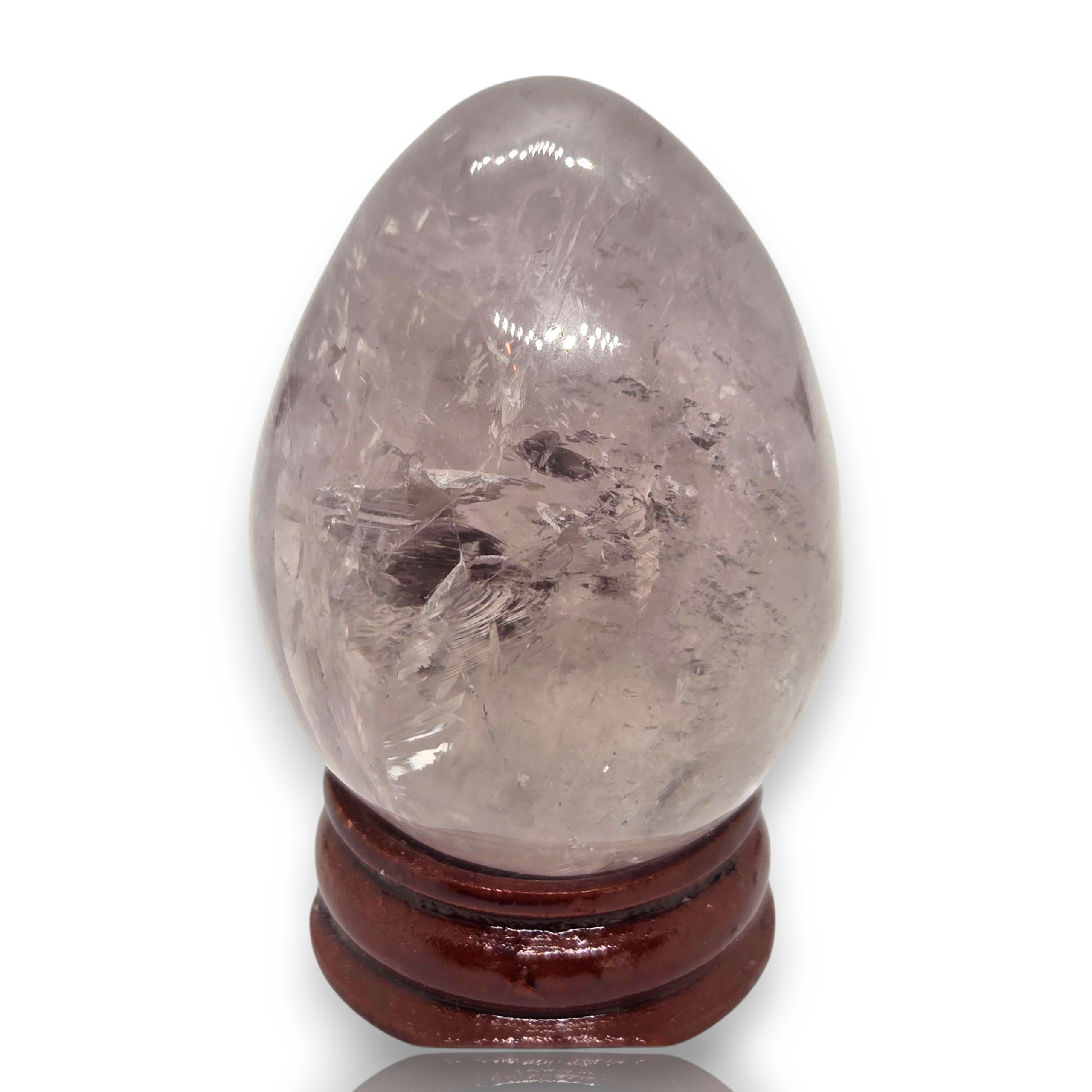 Crystal Chrysalis Haus  A polished light gray quartz crystal egg with visible internal needle-like inclusions, displayed on a dark brown wooden stand against a white background