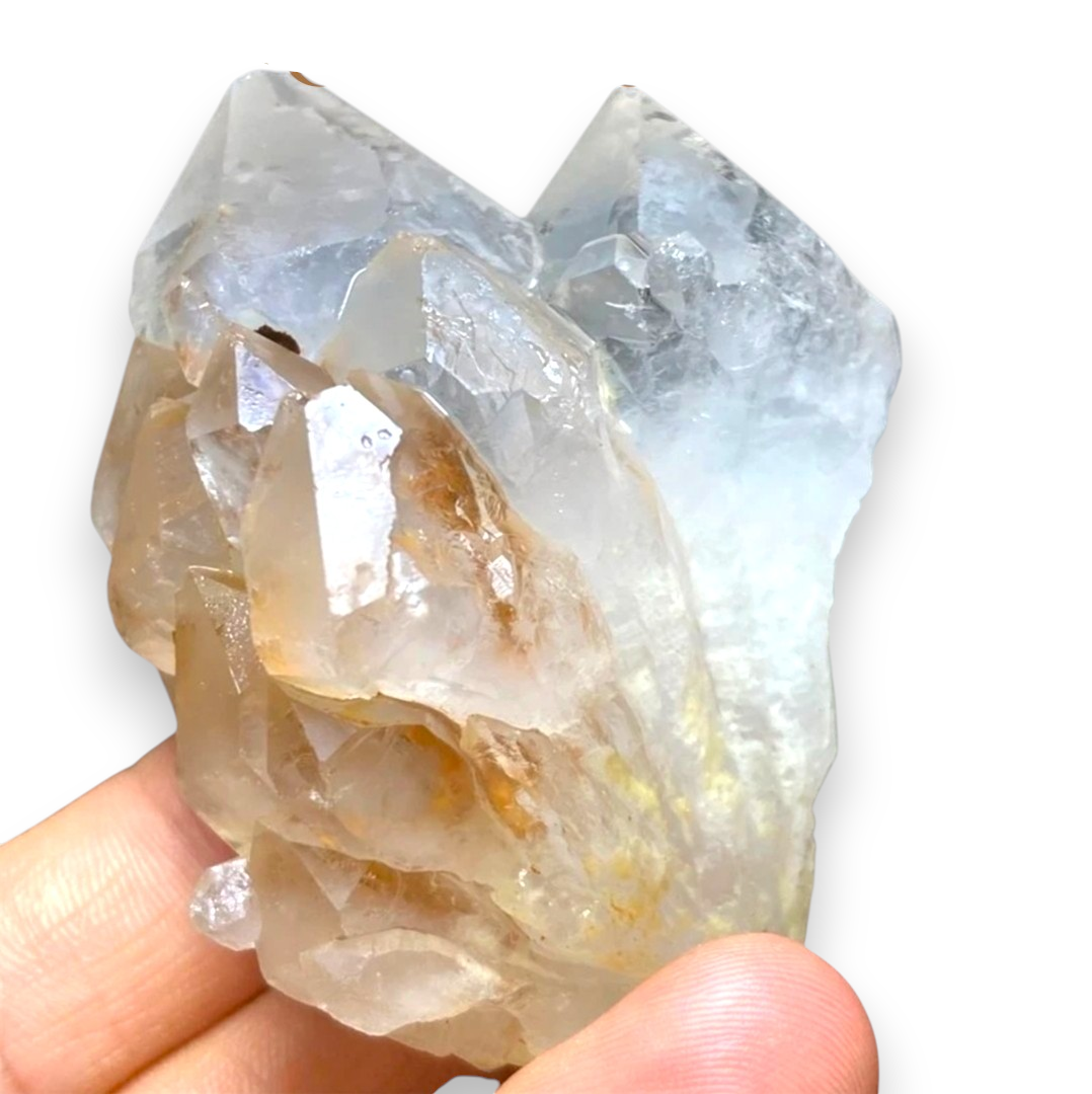 Crystal Chrysalis Haus A hand holding a large translucent crystal cluster with natural facets and some brown inclusions, photographed against a plain white background