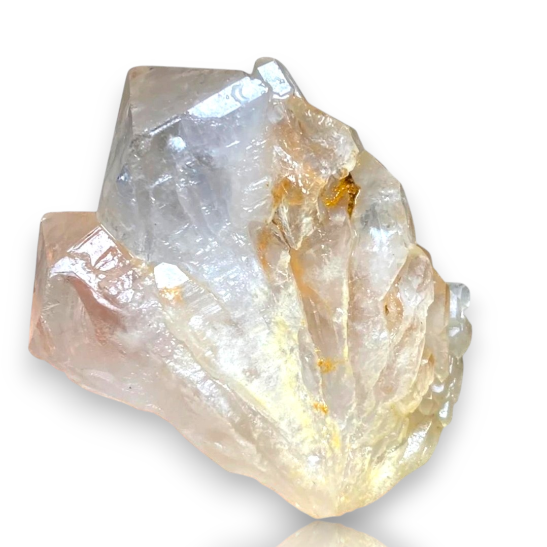 Crystal Chrysalis Haus A raw crystal cluster with clear, translucent quartz-like facets and subtle warm amber and pale pink tones, shown on a white background 