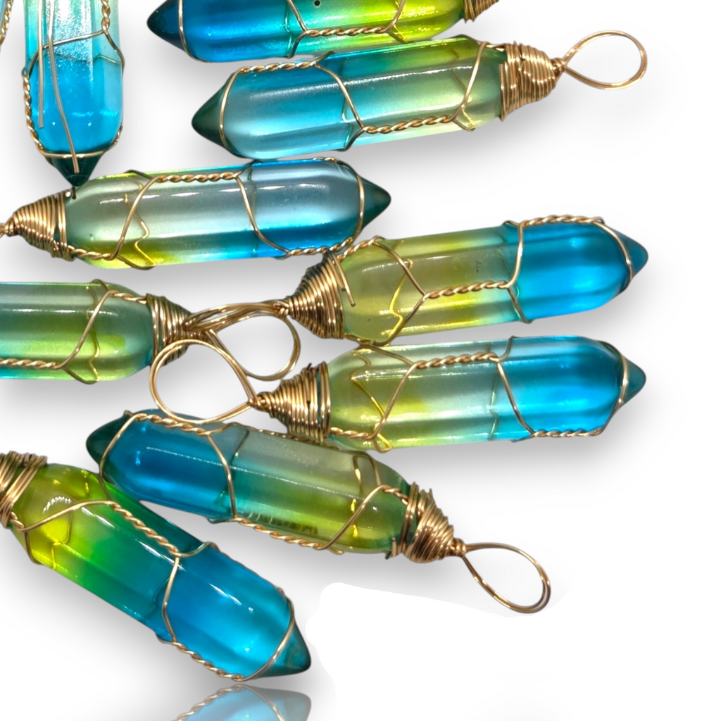 Crystal Chrysalis Haus Several glass crystal point pendants with a blue and green gradient, wrapped in gold wire with loop ends, arranged on a white background.