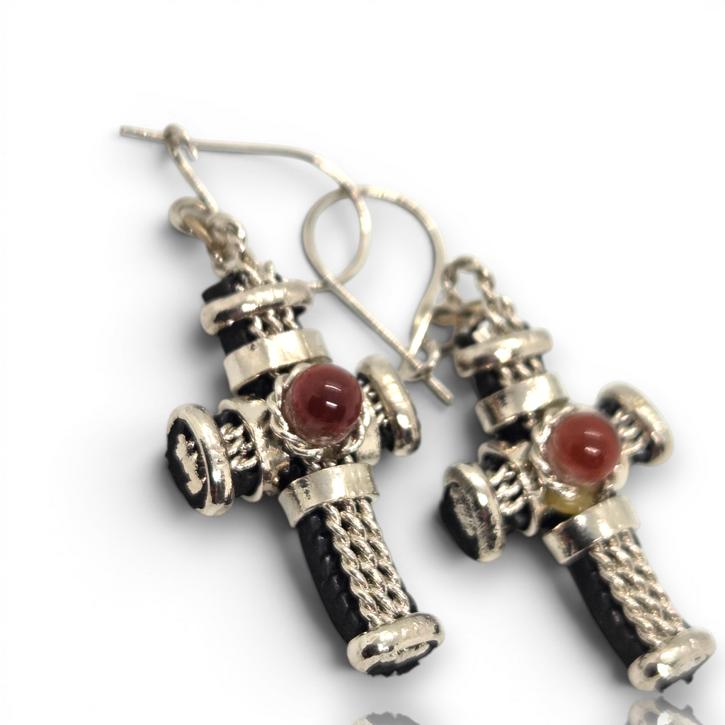 Crystal Chrysalis Haus A pair of dangling earrings with silver-toned metalwork, black textured details, and round reddish-brown stone accents, shown on a white background 