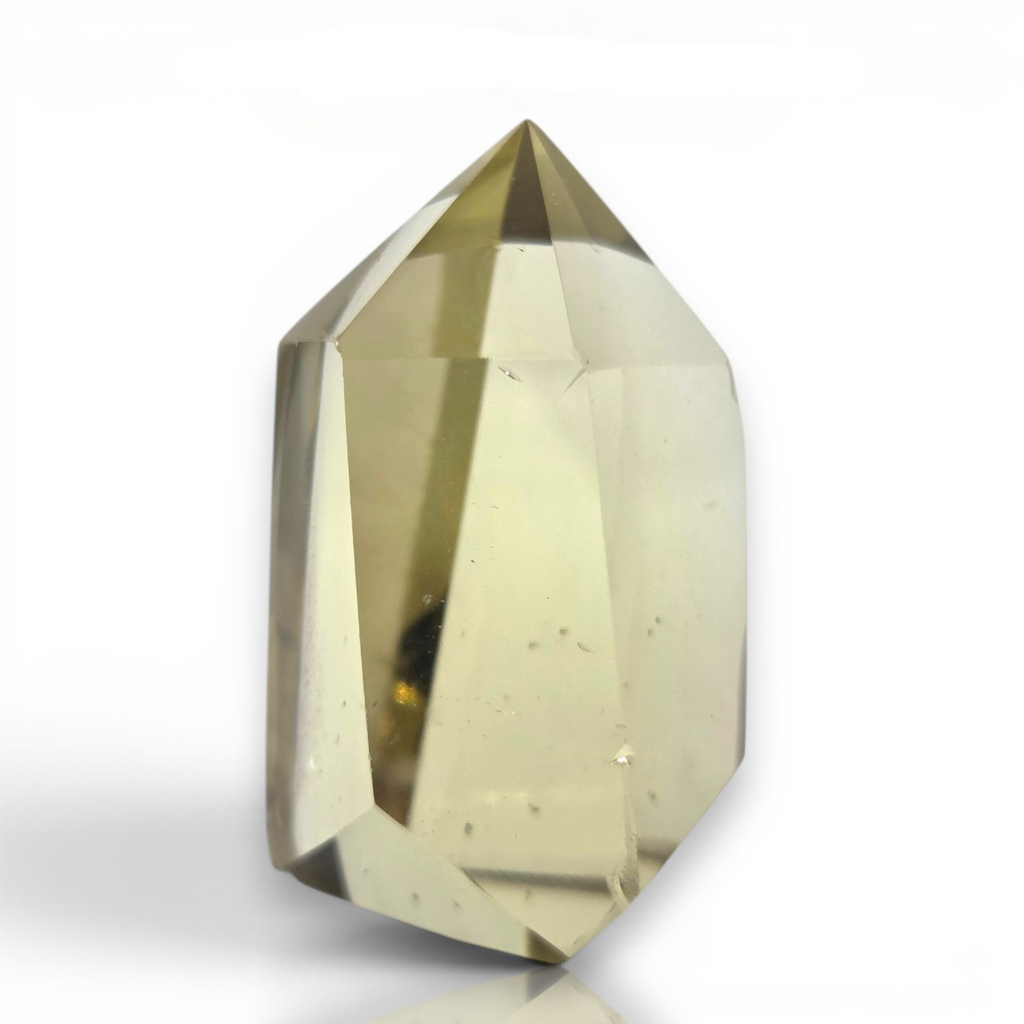 Crystal Chrysalis Haus A faceted, point-cut crystal gemstone with a pale yellow-green hue, shown on a clean white background 