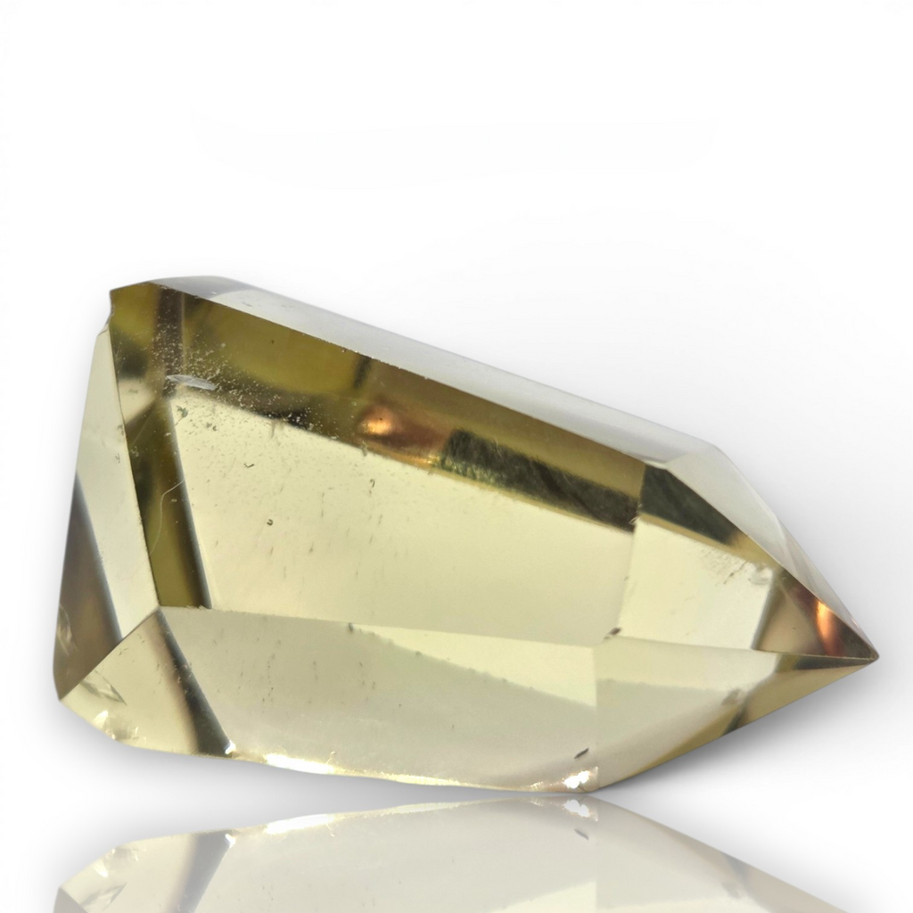 Crystal Chrysalis Haus A faceted clear crystal point with a warm yellow-tinted center, photographed on a white background