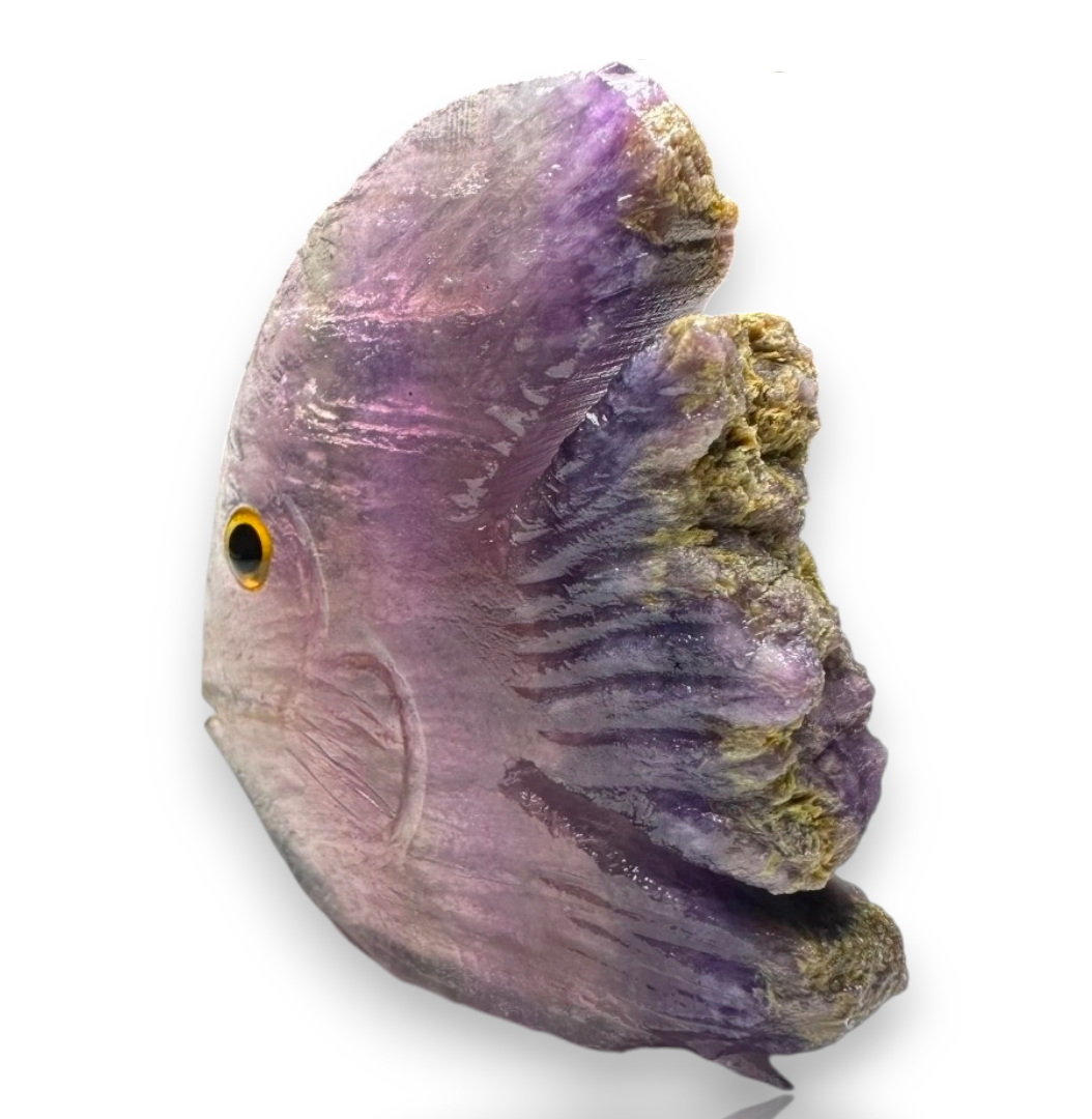 Crystal Chrysalis Haus A carved purple cat head figurine with a textured, natural stone appearance, featuring a small carved eye with a gold and black iris. The figurine is set against a plain white background 