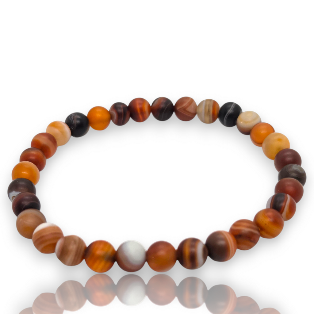 Crystal Chrysalis Haus A beaded stretch bracelet made of polished round beads in earthy brown, orange, black, and cream tones, arranged in a circle on a white background with a soft reflection below.