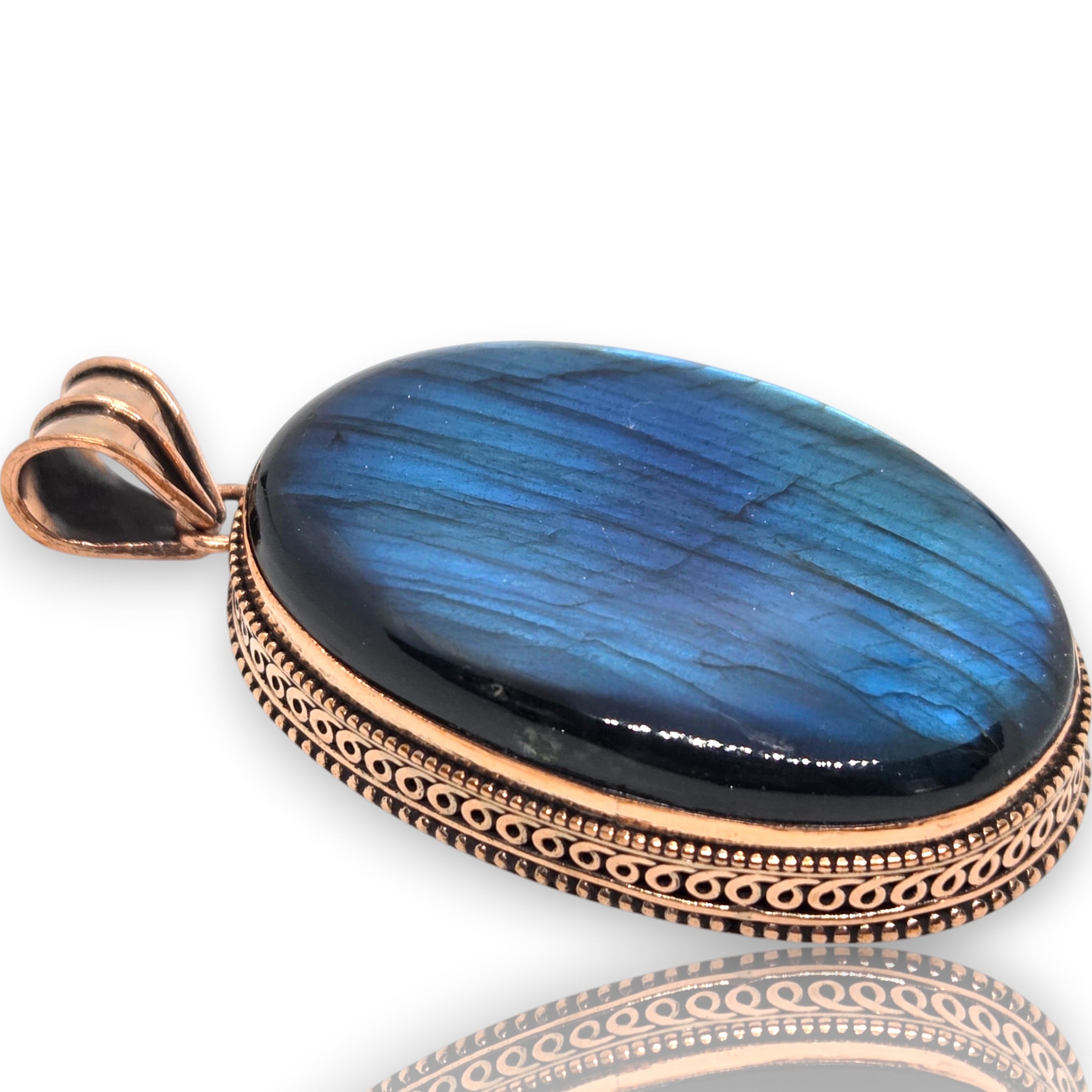 Crystal Chrysalis Haus An oval pendant featuring a vibrant blue labradorite stone with natural iridescent streaks, set in an ornate rose gold-toned bezel with a decorative bail.