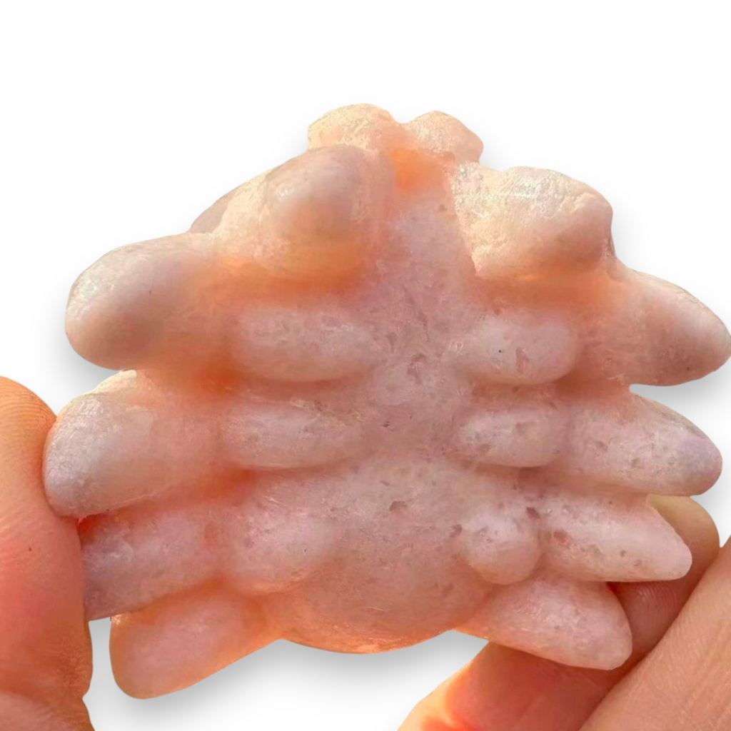 A pale pink textured cat scratcher held between two human hands against a white background