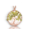 Crystal Chrysalis Haus A tree of life pendant featuring green stone chips arranged in a circular tree pattern, suspended in a copper wire frame with a matching top bail, shown on a white background with a soft reflection below.