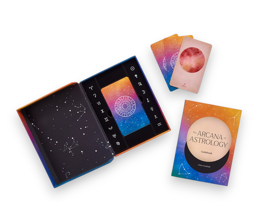 The Arcana Astrology Gold Book and its colorful cosmic-themed packaging, displayed alongside two cards on a clean white background