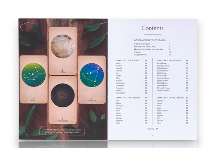 An open booklet or card deck spread displayed on a dark wood background with decorative leaves. The left side shows four astrology-themed cards with circular celestial illustrations, and the right side shows printed contents text.