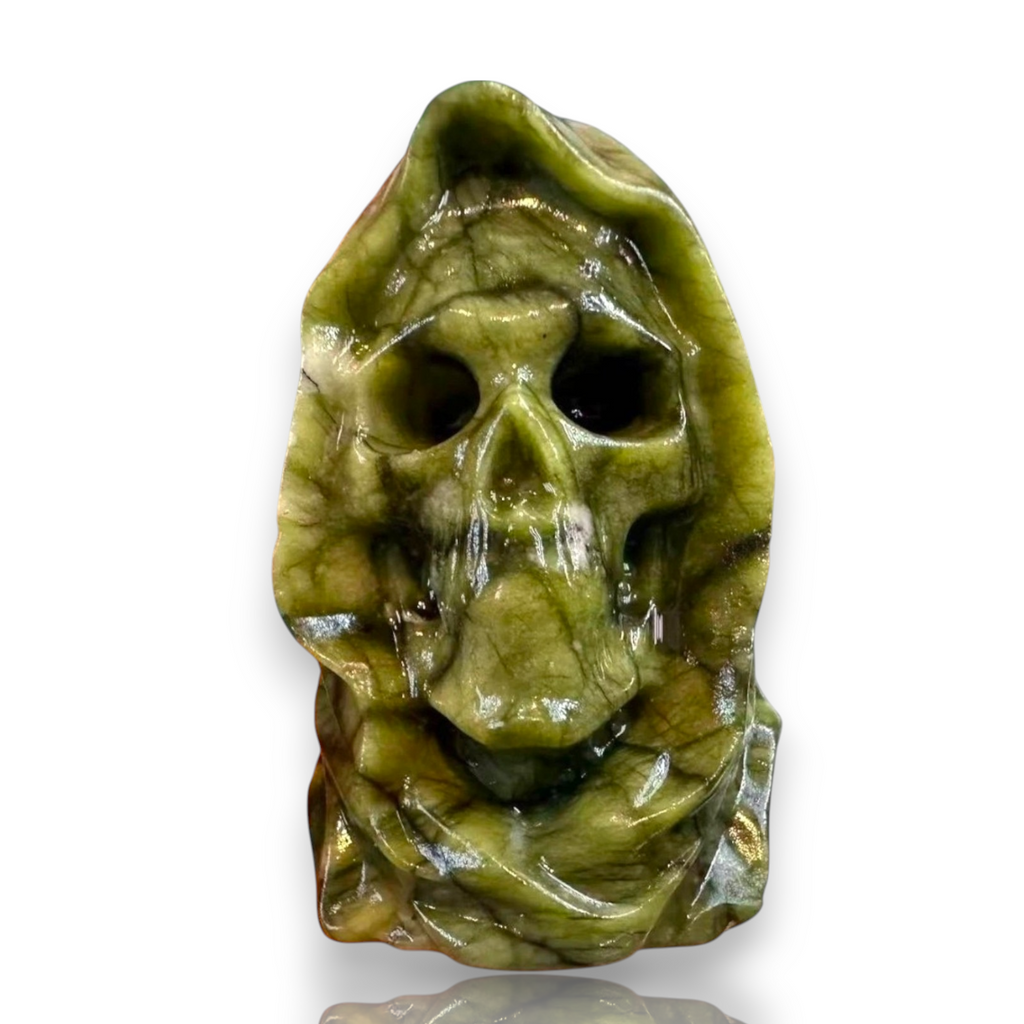 A carved green stone skull sculpture with a hooded, ghostly appearance, shown on a plain white background 