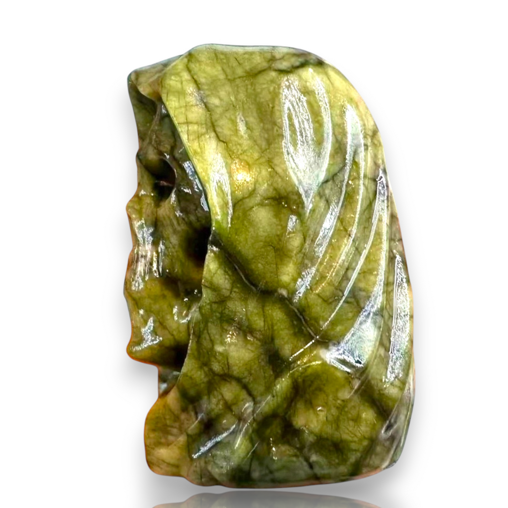 A polished green stone carving shaped like a stylized face, shown on a plain white background 