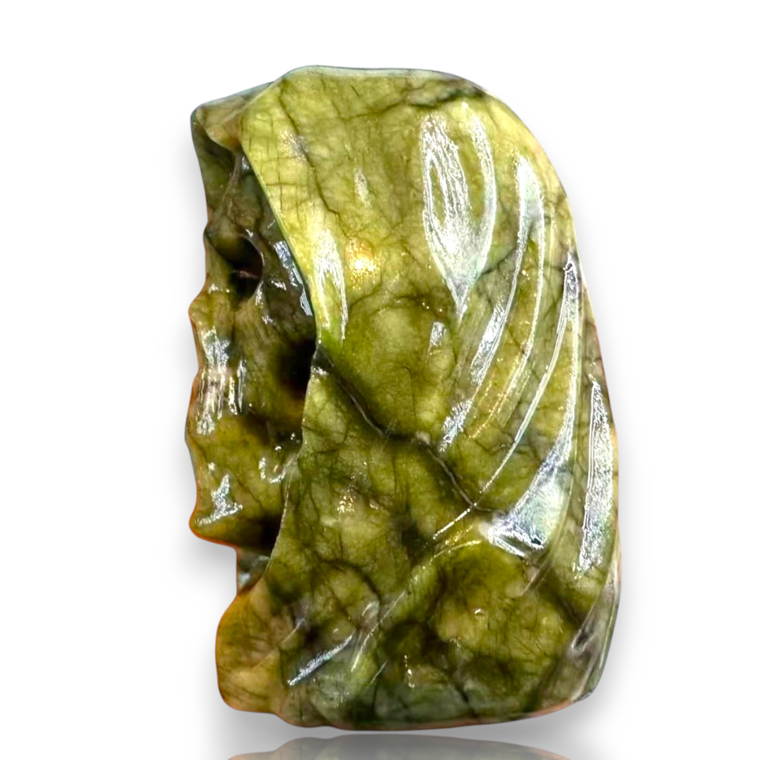 A polished green stone carving shaped like a stylized face, shown on a plain white background 