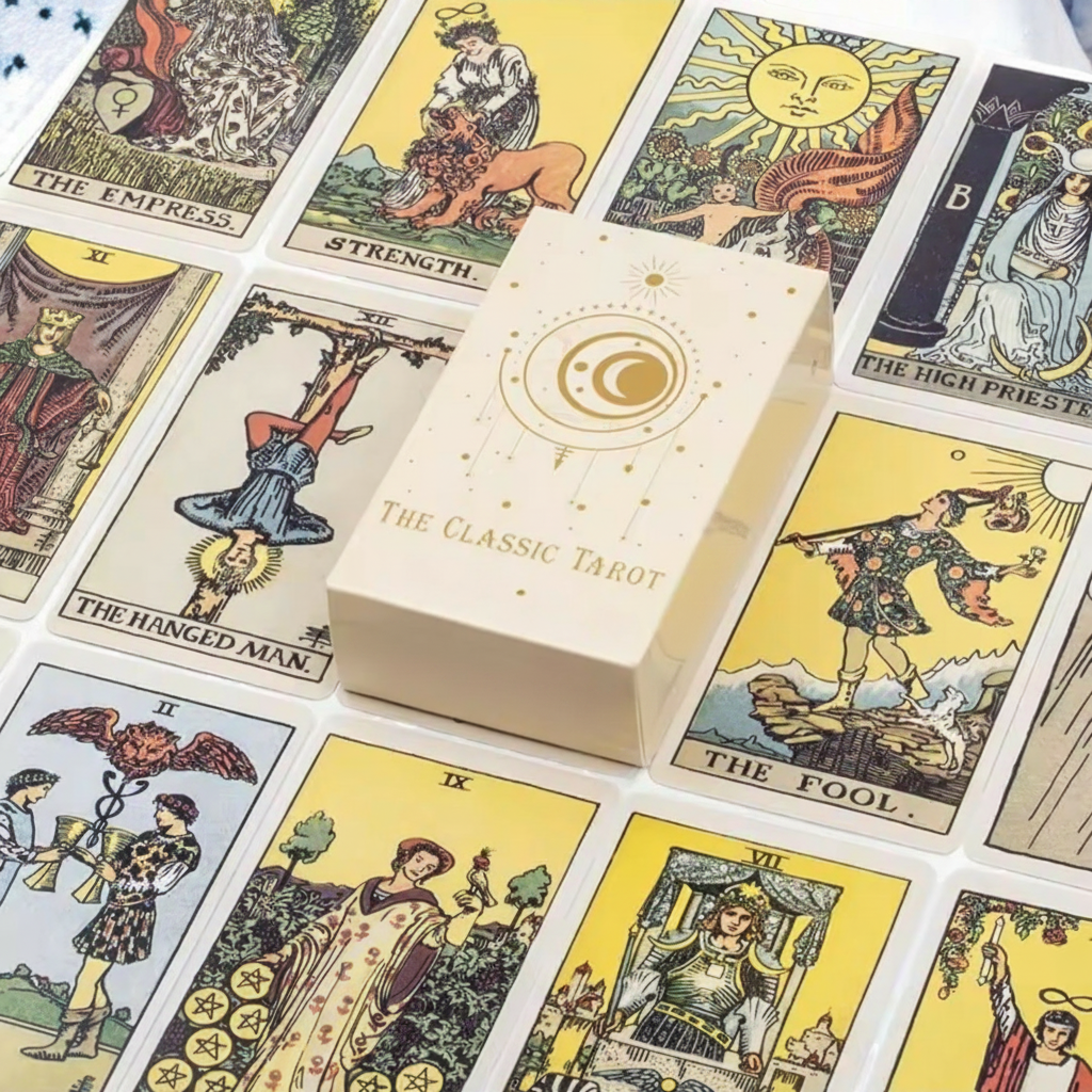 A cream-colored tarot card deck box labeled 'The Classic Tarot' and 'Cat's Ass Boutique' sits on top of several illustrated tarot cards, including The Empress, Strength, The Hanged Man, and The Fool.