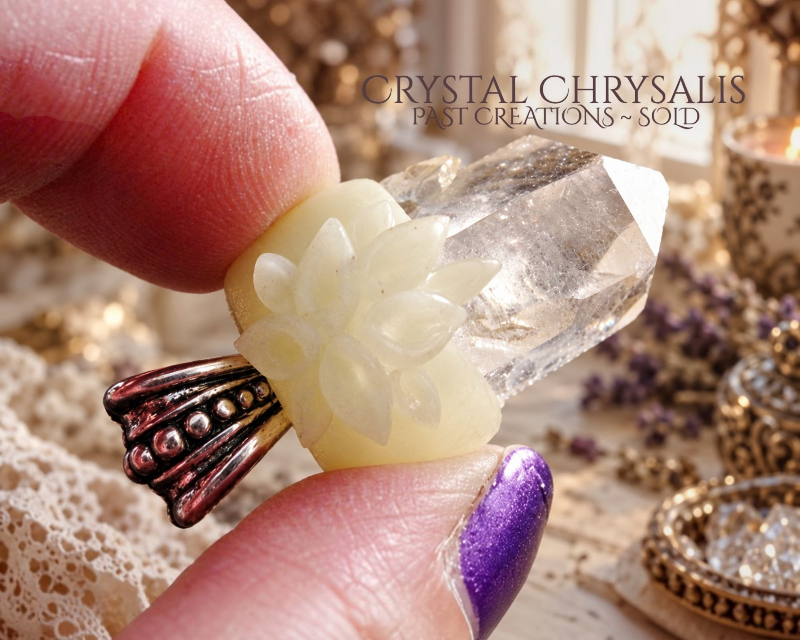 A handmade Quality  Customer Piece Crystal Chrysalis Natural Quartz Crystal Root Point Pendant is pictured. The background is a soft-focus bokeh of gold and cream tones with lace and decorative items.