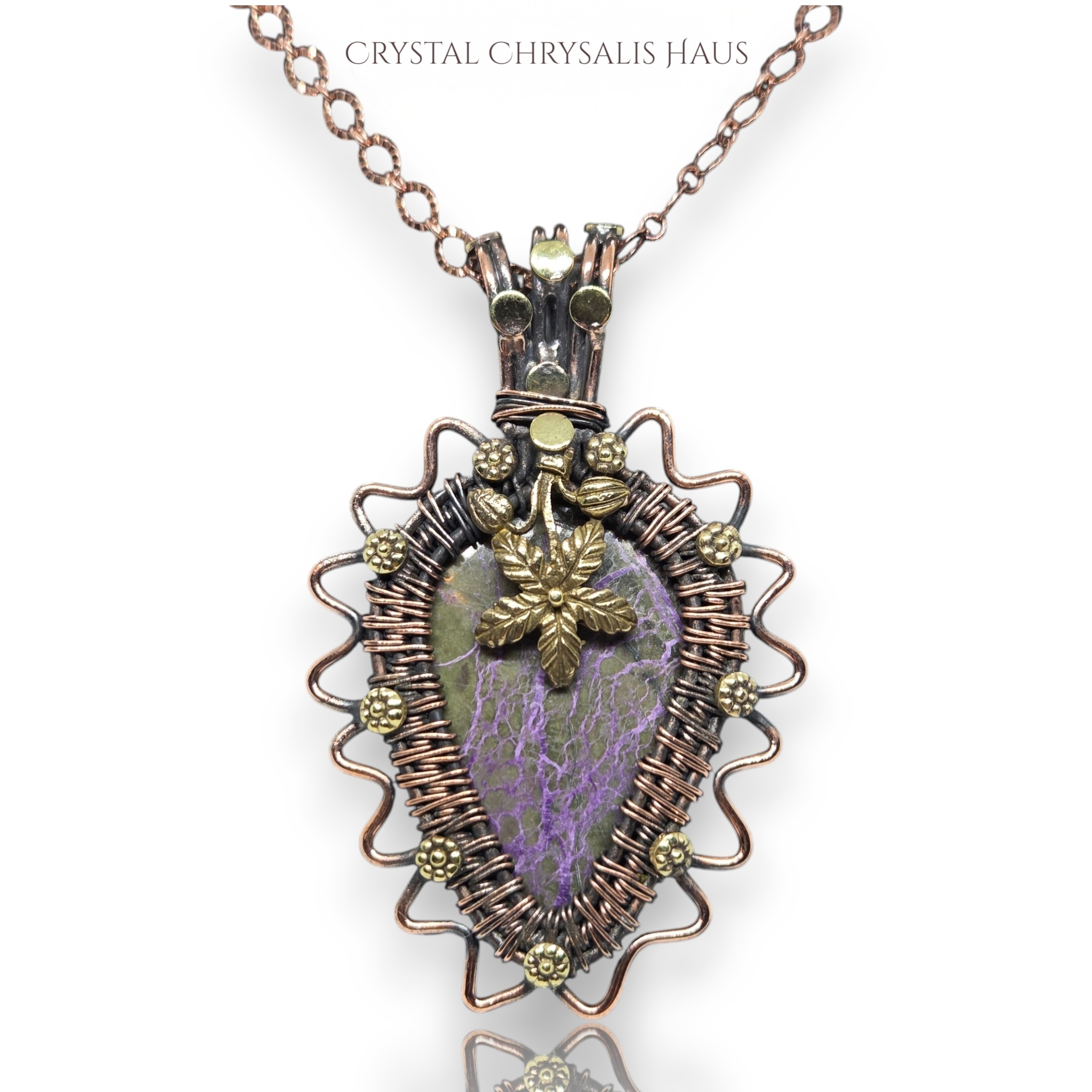 A handmade pendant necklace featuring a purple and green marbled stone wrapped in copper-toned wire, with a small gold leaf charm in the center, shown on a white background 